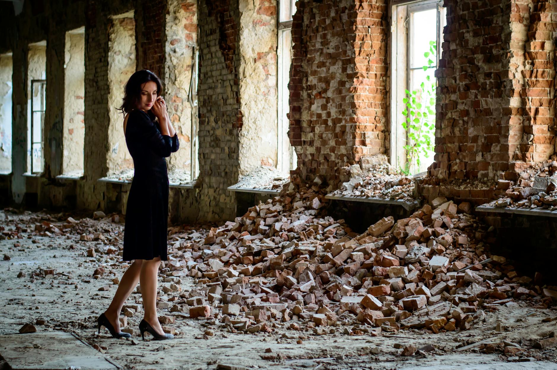 woman in black dress standing in front of pile of bricks