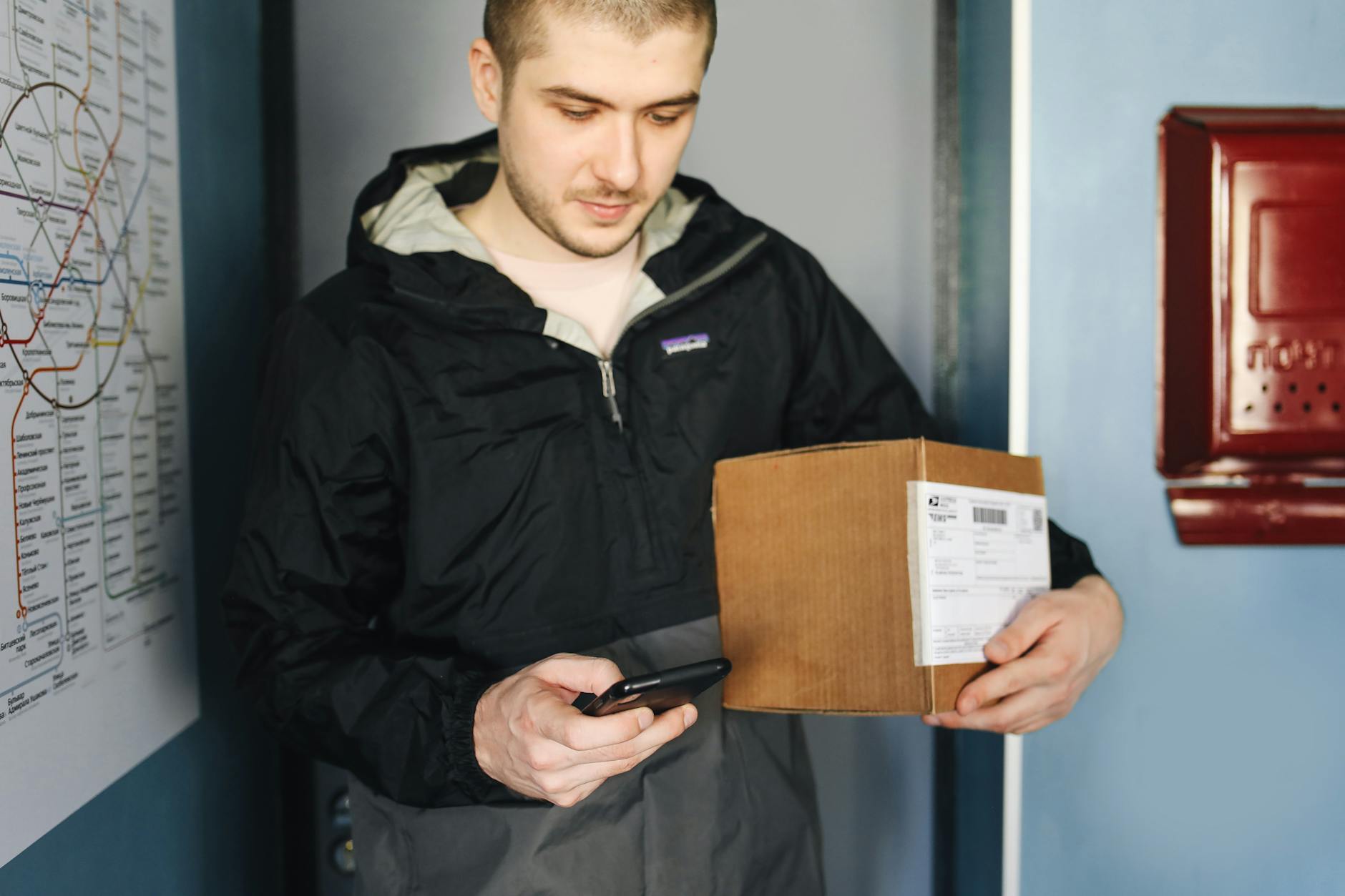 a man holding a cardboard box texting